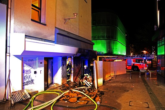 FW-E: Brennende Kartonagen vor Geschäftshaus, Feuer beschädigt die Fassade und droht auf ein Ladenlokal überzugreifen