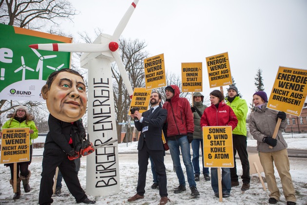 Protest gegen &quot;Gabriel-Bremse&quot; für Erneuerbare Energien / Protestaktion von BUND und Campact vor Schloss Meseberg: Person mit Gabriel-Maske sägt an Windrad (FOTO)