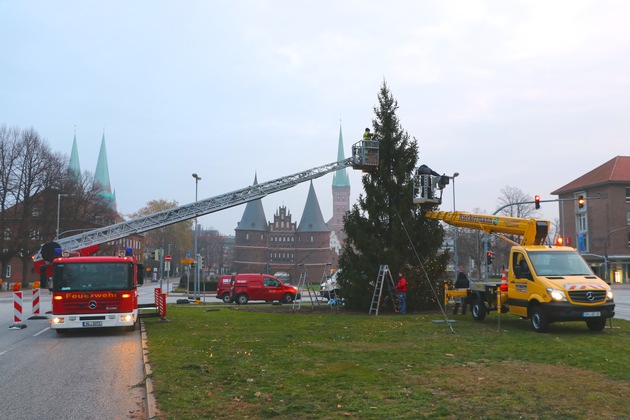 FW-HL: Weihnachtlicher Spezialeinsatz für Lübecks Feuerwehr / Brandschützer unterstützen mit Drehleiter das Aufstellen der &quot;Kotka-Tanne&quot;