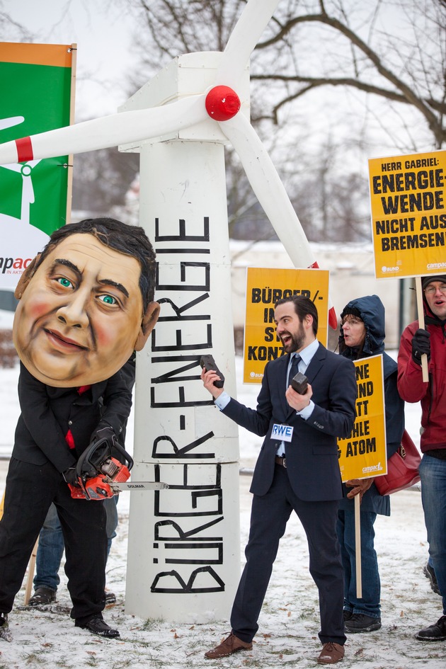 Protest gegen &quot;Gabriel-Bremse&quot; für Erneuerbare Energien / Protestaktion von BUND und Campact vor Schloss Meseberg: Person mit Gabriel-Maske sägt an Windrad (FOTO)