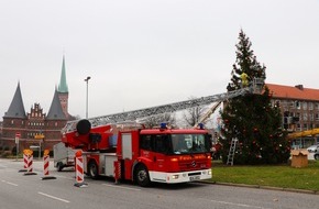 Feuerwehr Lübeck: FW-HL: Weihnachtlicher Spezialeinsatz für Lübecks Feuerwehr / Brandschützer unterstützen mit Drehleiter das Aufstellen der "Kotka-Tanne"