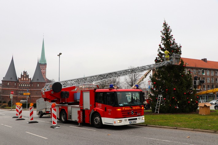 FW-HL: Weihnachtlicher Spezialeinsatz für Lübecks Feuerwehr / Brandschützer unterstützen mit Drehleiter das Aufstellen der &quot;Kotka-Tanne&quot;