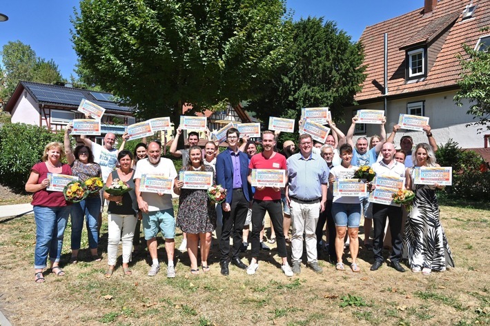 Bestes Wetter in Loffenau: 34 Monatsgewinner*innen freuen sich zusammen mit Glückbote Felix Uhlig (rotes Shirt) und Dr. Alexander Becker (rechts daneben), dem CDU-Landtagsabgeordneten des Landkreises Rastatt, sowie David Grässle (links daneben), Fraktionsvorsitzender der Freien Wähler Gemeinschaft in Loffenau, über 1,4 Millionen Euro. / Weiterer Text über ots und www.presseportal.de/nr/41583 / Die Verwendung dieses Bildes ist für redaktionelle Zwecke unter Beachtung ggf. genannter Nutzungsbedingungen honorarfrei. Veröffentlichung bitte mit Bildrechte-Hinweis.