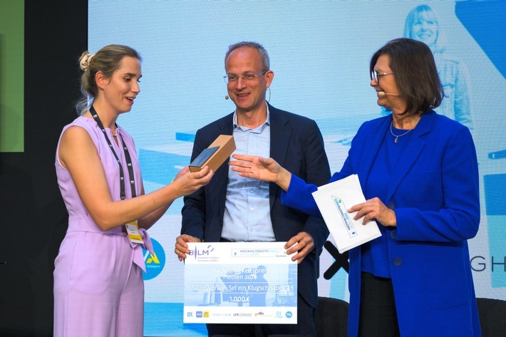 Nachhaltigkeitspreis Medien 2026: Sheena Cvrlje (links) vom Sailer Verlag wird für den Podcast "Sei ein Klugschnabel!" ausgezeichnet. Außerdem auf dem Foto: Der Präsident der Bayerischen Landeszentrale für neue Medien, Dr. Thorsten Schmiege, und die bayerische Landtagspräsidentin Ilse Aigner. / Weiterer Text über ots und www.presseportal.de/nr/8218 / Die Verwendung dieses Bildes für redaktionelle Zwecke ist unter Beachtung aller mitgeteilten Nutzungsbedingungen zulässig und dann auch honorarfrei. Veröffentlichung ausschließlich mit Bildrechte-Hinweis.