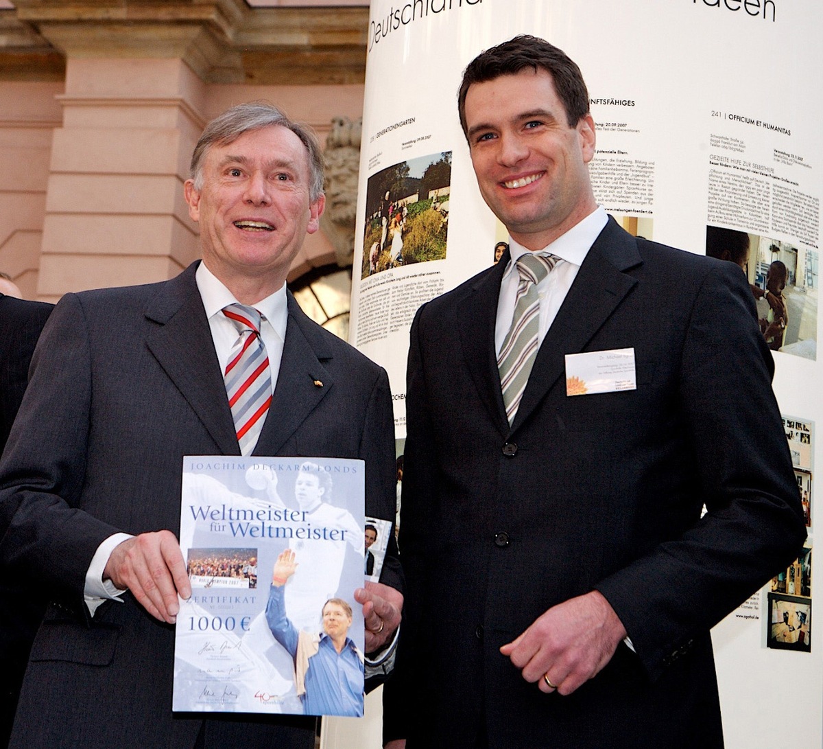 Bundespräsident Horst Köhler nimmt das Deckarm-Zertifikat &quot;Weltmeister für Weltmeister&quot; mit der laufenden Nr. 1 von Sporthilfe-Geschäftsführer Dr. Michael Ilgner entgegen.